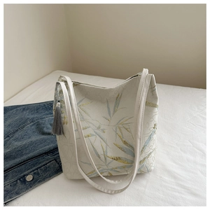 Close-up of bamboo embroidery on the off-white canvas tote bag with a grey tassel detail