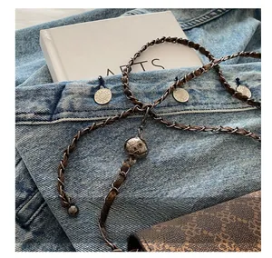 Detail of adjustable metal sphere buckle and braided chain strap on vintage brown bag