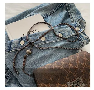 Detail of clover print handbag with chain strap and decorative engraved metal ball