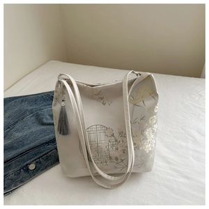 Detailed close-up of white tote bag with floral patterns and grey tassel ornament