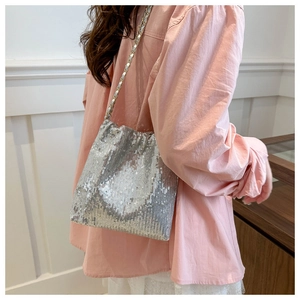 Close-up of silver sequin bucket bag with metal chain strap on pink shirt background
