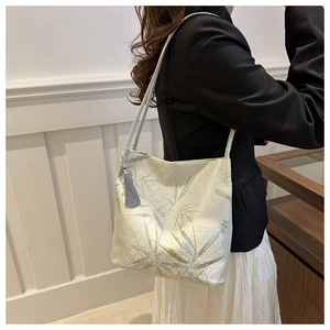 Detail of bamboo embroidery on beige tote bag with a grey silk tassel accent
