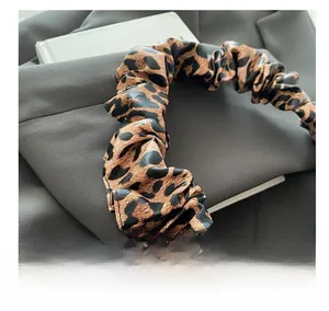 Macro shot of the pleated leopard print fabric texture on a stylish scrunchie accessory