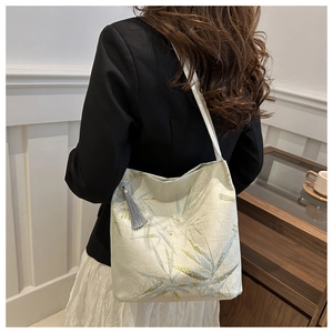 Detail view of oriental tote with bamboo embroidery and tassel worn by a model