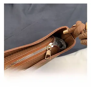 Detail showing golden metal zipper and herringbone embossed brown leather on shoulder bag