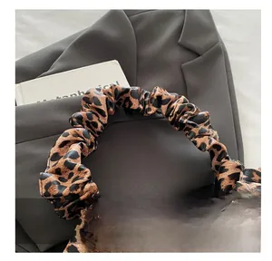 Detail showing plush pleated handle of leopard print crescent bag on a grey blazer