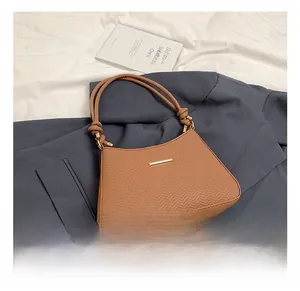 Close-up of caramel shoulder bag featuring herringbone texture and gold hardware detail