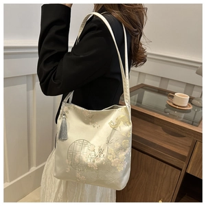 Detail of elegant Chinese style embroidery and silk tassel on beige shoulder bag