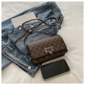 Detailed view of the brown geometric pattern and metallic buckle on the leather bag