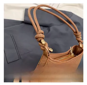 Detail of adjustable woven strap and gold metal hardware on caramel shoulder bag