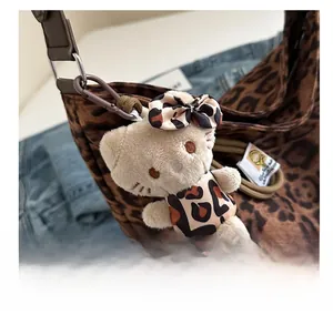Detail view of a leopard print plush Hello Kitty charm with brown clip on a handbag