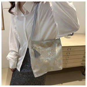 Close-up of golden embroidery landscape pattern and grey tassel on the bucket bag