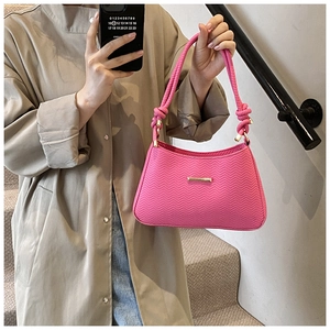 Detail of rose pink handbag with wavy chevron texture and knotted rope shoulder strap
