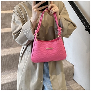 Detail of pink textured shoulder bag with twisted rope handles and golden hardware