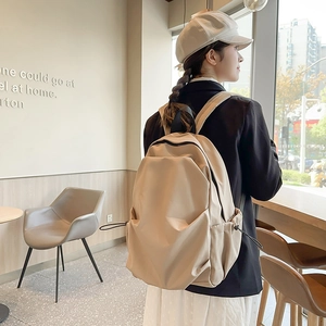 Detail view of a beige minimalist laptop backpack with adjustable drawstring side pockets