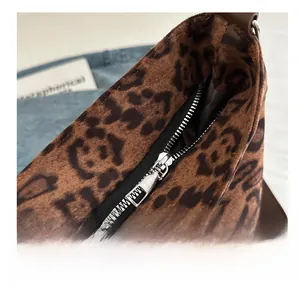 Detailed close-up of smooth silver zipper and leopard print faux fur texture on the bucket bag