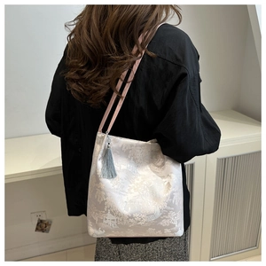 Detail of embroidered landscape jacquard tote bag with pink straps and blue tassel charm