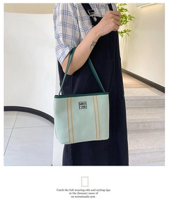 Detail view of mint green canvas tote bag with orange stripes and logo patch