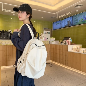 Detail view of the cream white minimalist backpack featuring side drawstring pockets and texture