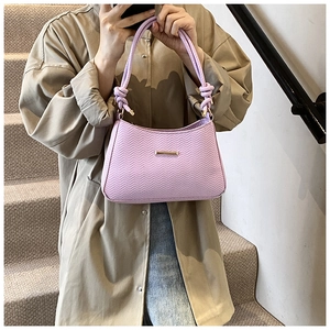 Close-up of lilac quilted handbag featuring woven handles and gold metal accent detail
