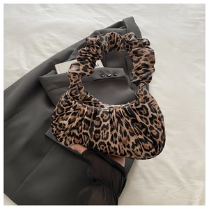 Detailed view of leopard print crescent bag with stylish scrunchie handle on fabric