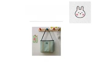 Detail showing the light green canvas fabric with cute rabbit embroidery and square label