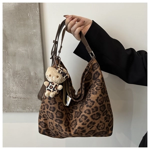 Detail of leopard print hobo bag with a plush cat charm and adjustable leather strap