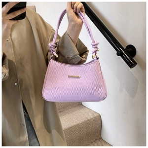 Detailed view of the purple woven shoulder bag with golden brand plate and knotted rope handle