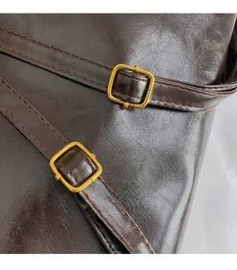 Detail shot of deep brown faux leather tote bag with vintage brass buckles and stitching