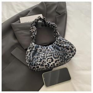 Close-up of leopard print ruched cloud bag on a suit with a phone for scale