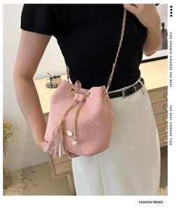 Detail view of pink bucket bag with suede texture, fringe tassel and pearl chain