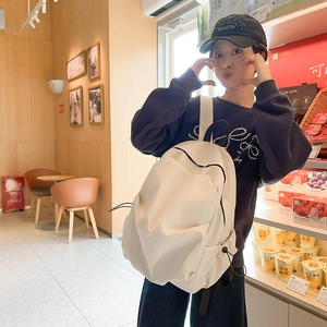 Detailed view of a white minimalist backpack with drawstring side pockets in a lifestyle setting
