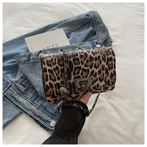 Detail of leopard print crossbody bag with gunmetal twist lock and chain strap on denim