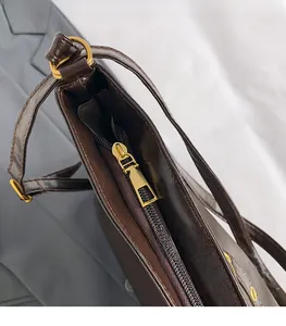 Detail of premium gold-tone zipper hardware and dark brown faux leather on tote bag