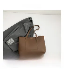 Close-up of brown faux leather tote bag showing fine stitching and metal logo details