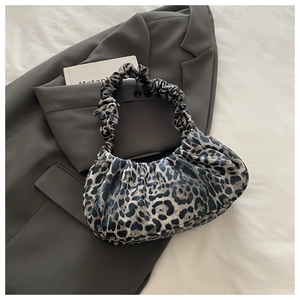 Detail of leopard print crescent bag with ruffled strap on a grey suit and books
