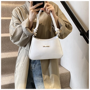 Detail showing white woven texture and gold logo bar on minimalist shoulder bag
