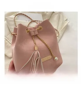 Detail of pink drawstring bucket bag showing gold chain strap and pearl tassel accessory