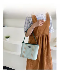 Detail of light green canvas tote bag with brown stripes and MIDU 2ND brand label