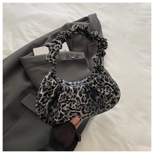 Close-up of leopard print crescent bag with pleated handles on a grey blazer