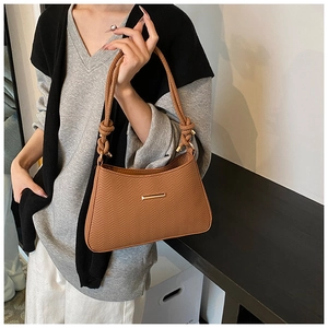 Close-up of caramel brown shoulder bag featuring textured chevron pattern and knotted handle