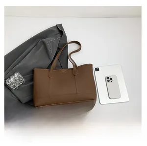 Flat lay of large brown leather tote bag showing spacious interior with tablet and accessories