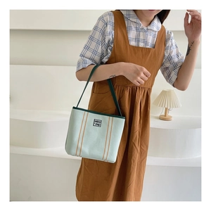 Detail shot of green canvas bucket bag with brown stripes and MIDU logo label