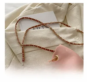 Close-up of pink bucket bag with gold chain and leather interwoven shoulder strap detail
