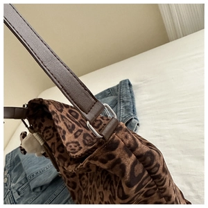 Detail of leopard print bucket bag with plush bear charm and brown leather strap
