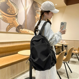 Side view of a large black casual backpack with drawstring pockets in a cafe setting