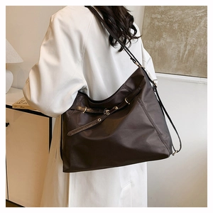 Detail of dark brown tote bag showing smooth fabric texture and metal eyelet buckle strap