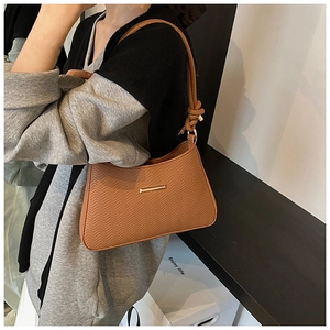 Detailed macro view of brown herringbone embossed texture and gold metal buckle on shoulder bag