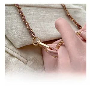 Detailed close-up of pink bucket bag showing golden chain strap and lobster clasp detail
