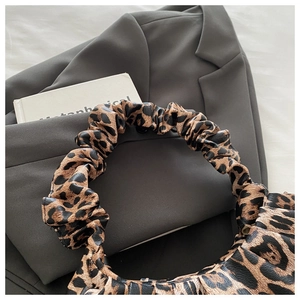 Macro shot of stylish leopard print cloud bag with ruched handle on grey blazer